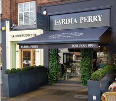 a store front with plants and chairs outside