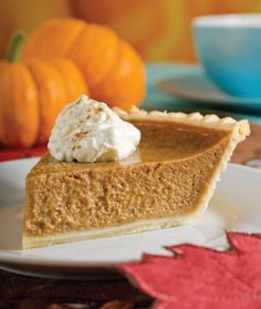 a slice of pumpkin pie on a plate with whipped cream and maple leaves around it