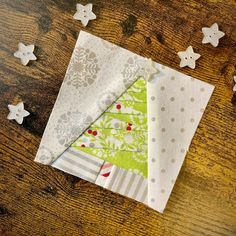 three pieces of fabric sitting on top of a wooden table next to small white stars