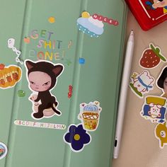 an open notebook with stickers on it next to a pen and some magnets