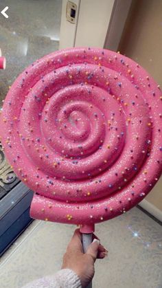 a person holding a giant pink object with sprinkles on it