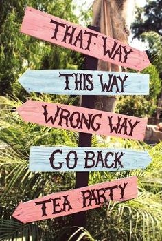 a wooden sign that says, that way wrong way go back tea party