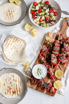 several plates with food on them, including pita bread and salad