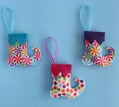 three colorful christmas stockings hanging from hooks on a blue wall with snowflakes