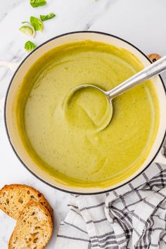 a bowl filled with soup next to a piece of bread and a spoon in it