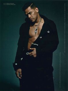 a shirtless man in a black jacket and chain around his neck posing for the camera