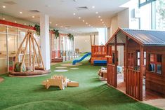 An indoor childcare playground with grass as the floor and a mini wooden house and slide. House Slide, Montessori Playroom, Newcastle Nsw, Outdoor Play Area