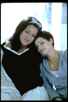 two women sitting next to each other on a bed