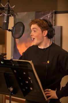 a man with headphones standing in front of a microphone and singing into a mic