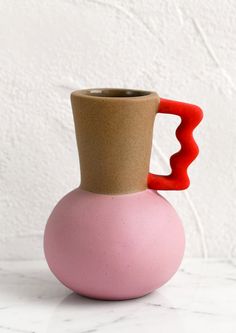 a pink and brown vase sitting on top of a white table