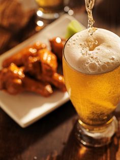 a glass filled with beer next to some food