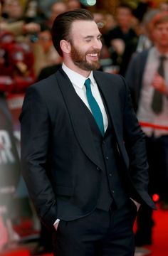 a man in a suit and tie standing on a red carpet