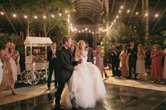 a bride and groom walking down the aisle at their wedding reception with guests in the background