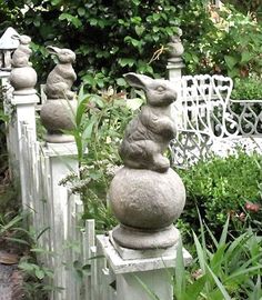 several stone rabbits are sitting on top of each other in front of a white fence