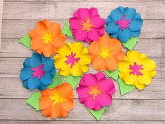 colorful paper flowers arranged on top of each other in the middle of a wooden table