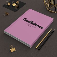 a pink notebook with the word goddiene on it next to some gold objects