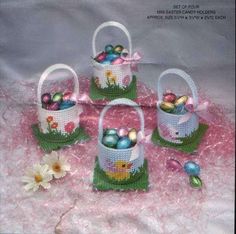 four baskets filled with easter eggs on top of a pink cloth covered table next to flowers