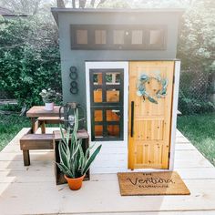 a small house with a potted plant next to it and the door is open