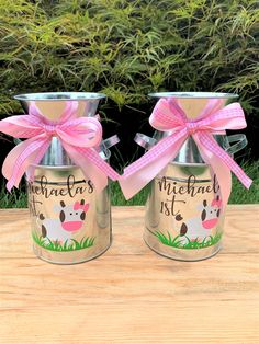 two metal jars with pink bows on them