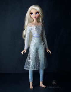 a doll with blonde hair wearing a blue dress and white shoes, standing in front of a black background