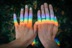 two hands with multicolored nail polish holding each other's fingers in the air