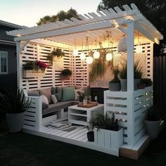 a white pergoline with lights on it and potted plants in the corner