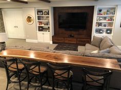 a living room filled with furniture and a flat screen tv mounted on a wall above a wooden bar