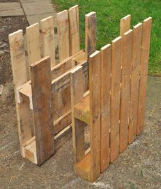 a wooden bench made out of pallets sitting on the side of a road next to grass