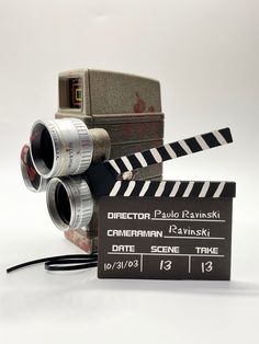 an old movie projector sitting on top of a clapper next to a camera