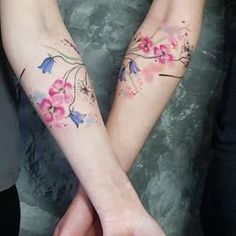 two people are holding hands with tattoos on their arms and the other hand has flowers painted on it