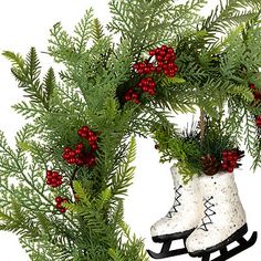 a pair of white snow boots sitting on top of a green wreath with red berries and pine cones