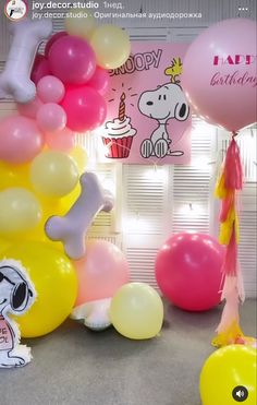 balloons and decorations for a birthday party with snoopy characters on the wall behind them