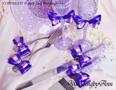 a table topped with purple bows and silverware next to a plate covered in pearls