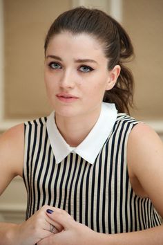 a woman sitting at a table with her hands on her chest and looking off to the side