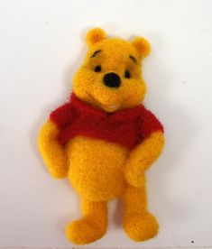 a yellow stuffed animal with a red scarf around it's neck and chest, sitting on a white surface