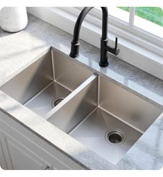 two stainless steel kitchen sinks with black faucets in front of a large window