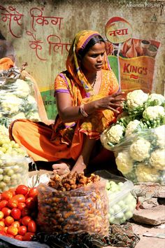 a woman sitting on the ground surrounded by fruits and vegetables