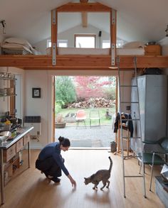 a woman is playing with her cat in the living room and on the kitchen floor