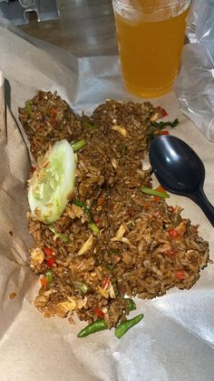 there is rice and vegetables on the table next to a glass of beer with a spoon