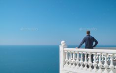 a man sitting on a balcony looking out at the ocean - stock photo - images