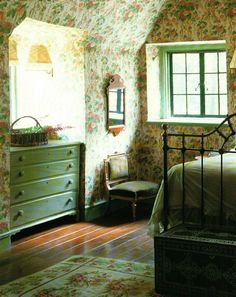 a bedroom with floral wallpaper and green dressers in the corner, along with an antique style bed