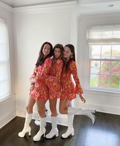 three young women in matching outfits posing for a photo with their arms around each other