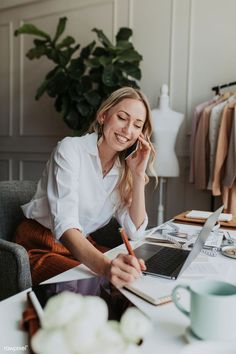 a woman sitting at a desk talking on the phone and working on her laptop computer