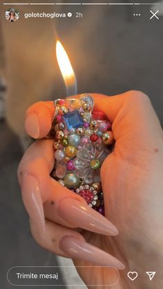 a person holding a small lighter with beads on it's side and a candle in the middle