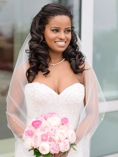 a woman in a wedding dress holding a bridal bouquet and smiling at the camera