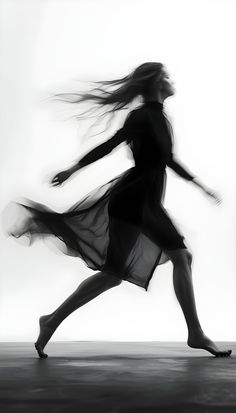 a black and white photo of a woman dancing with her hair blowing in the wind