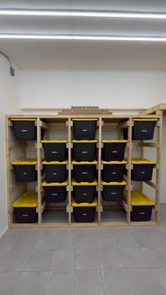 several black and yellow bins are on shelves in a room with tile flooring