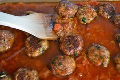 meatballs and sauce in a pan with a wooden spoon