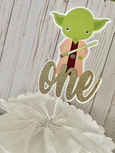 a cake topper with the word one on it and an image of yoda