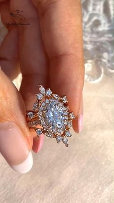 a woman's hand holding an engagement ring with diamonds on the top and bottom